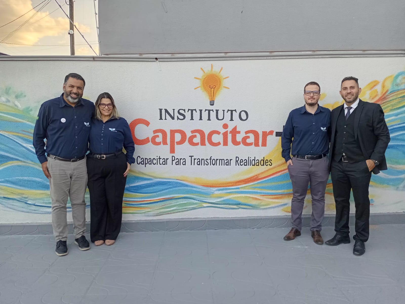 Diretoria do Instituto Capacitar Mais reunida em frente ao logotipo da instituição
